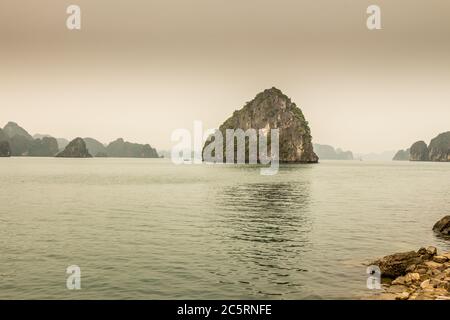 Kalkstein Karst Insel und Ufer an einem nebligen Tag in der UNESCO-Weltkulturerbe der Ha Long Bay, in Vietnam Stockfoto