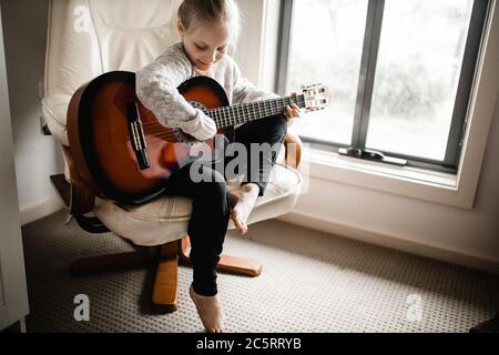 Ein junges kaukasusmädchen, das beim Gitarrenspiel übt Stockfoto