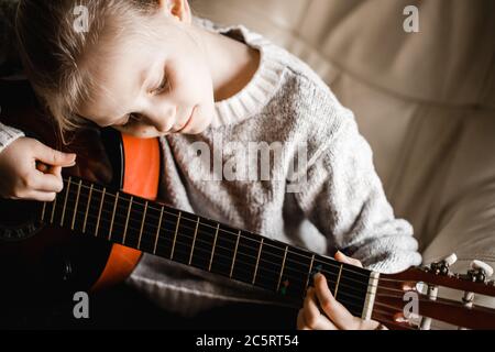 Ein junges kaukasusmädchen, das beim Gitarrenspiel übt Stockfoto