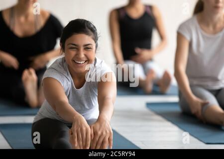 Glückliche junge indische Frau in sitzenden nach vorne beugen Position. Stockfoto