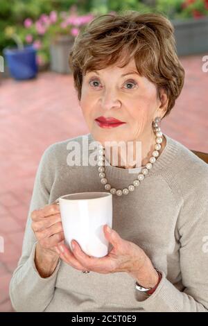 Achtzig Jahre alte Frau, die einen Becher hält Stockfoto