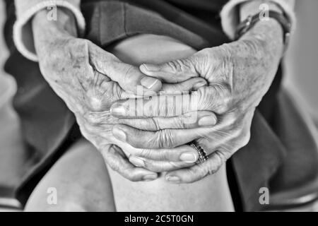 Ältere Frau mit verbundenen Händen sitzend Stockfoto