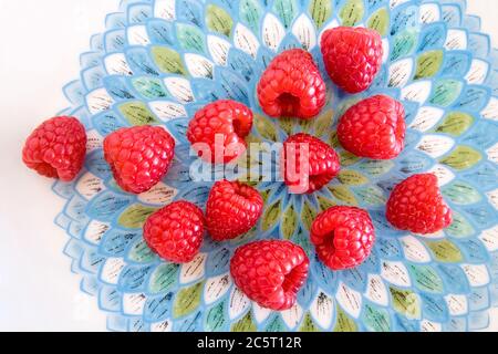 Himbeeren auf einem farbigen Porzellanteller Stockfoto