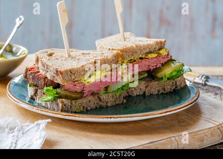 Rindfleisch-Sandwich mit eingelegter Gurke und Senfkartarsauce in zwei Hälften geschnitten Stockfoto