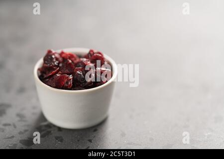 Getrocknete Preiselbeeren in einer Schüssel auf Beton Hintergrund Stockfoto