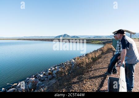 Touristen schauen auf Ross River Dam mit hohem Wasserstand, Berge im Hintergrund Stockfoto