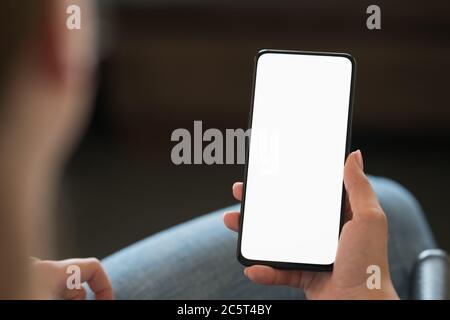 Junge Frau sitzt im Stuhl mit modernem Smartphone mit weiß Angezeigt Stockfoto