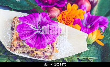 Süß mit Malbe und Mandeln.Teller mit Malwee Blumen verziert. Blumenfutter Konzept. Essbare Sommerblumen Stockfoto