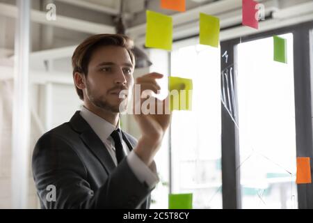 Fokussierte männliche Mitarbeiter arbeiten mit Haftnotizen entwickeln Geschäftsplan Stockfoto