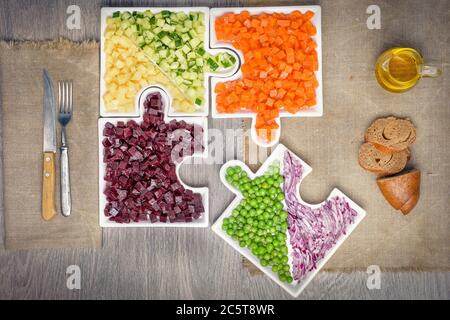 Rohes Gemüse Karotten, Erbsen, Zwiebeln, Gurken, Kartoffeln, in Würfel geschnittene Rüben liegen auf Platten, die in Puzzles gesammelt werden. Stockfoto