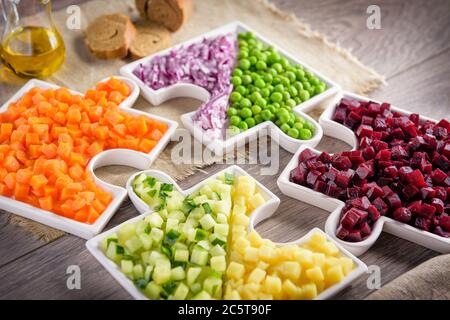 Rohes Gemüse Karotten, Erbsen, Zwiebeln, Gurken, Kartoffeln, in Würfel geschnittene Rüben liegen auf Platten, die in Puzzles gesammelt werden. Stockfoto