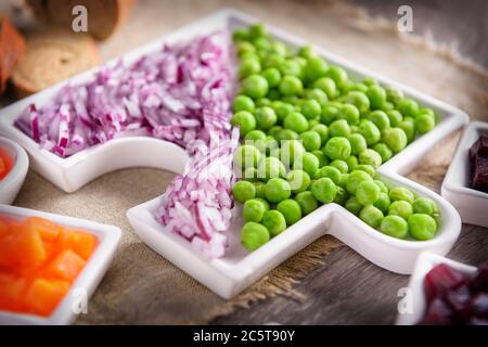 Rohes Gemüse Zwiebeln und Erbsen, ​​lying auf einem Teller geschnitten. Nahaufnahme. Stockfoto