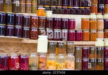 Kompott, Marmelade, Konfitüren und traditionelle georgische Saucen aus Beeren, Obst und Gemüse zu Hause. Konserven in Gläsern und Flaschen auf dem Regal von Stockfoto