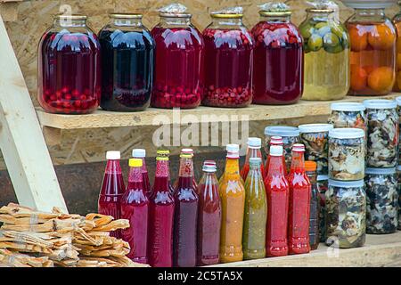 Kompott, Marmelade, Konfitüren und traditionelle georgische Saucen aus Beeren, Obst und Gemüse zu Hause. Konserven in Gläsern und Flaschen auf dem Regal von Stockfoto