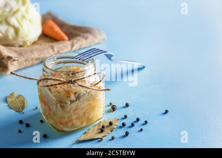 Fermentiertes Gemüse. Sauerkraut. Karotten, Pfeffer, Lorbeer-Zutaten auf blauem Hintergrund Stockfoto