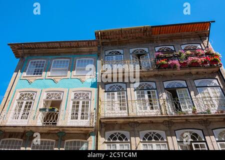 Guimarães, Portugal - schöne erhaltene mittelalterliche bunte traditionelle Steinhäuser mit Holzfenstern und kleinen Balkonen und Blumentopf Stockfoto