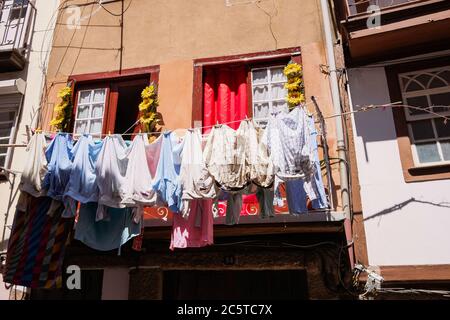 Guimarães, Portugal - schöne erhaltene mittelalterliche bunte traditionelle Steinhäuser mit Holzfenstern und kleinen Balkonen und Blumentopf Stockfoto