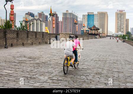Xian, Provinz Shaanxi / China - 4. August 2015: Menschen fahren Fahrräder auf der größten und am besten erhaltenen alten Stadtmauer von Xian Stockfoto