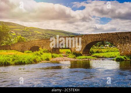 Alte Steinbrücke am Fluss Suir in der Grafschaft Tipperary, Irland, Comeragh Mountains in der Grafschaft Waterford im Hintergrund. Stockfoto