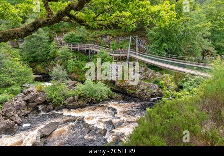 ROGIE FALLS RIVER BLACK WATER ROSS-SHIRE HIGHLANDS SCHOTTLAND IM SOMMER MIT MENSCHEN ÜBER DIE FUSSBRÜCKE ÜBER DEN UNTEREN TEIL DER WASSERFÄLLE Stockfoto