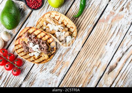 Set aus exican Taco mit Rindfleisch und Hühnerfleisch und Zutaten, über weiß strukturierte Holzoberfläche Hintergrund, Draufsicht, Platz für Text. Stockfoto