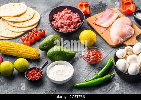 Taco Zutaten hausgemachte Küche mit Gemüse und Huhn Rindfleisch und Schweinefleisch, Mais, Pilze auf grauem Hintergrund Seitenansicht. Stockfoto