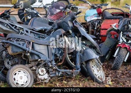 Die alten zerbrochenen rosteten Fahrräder, Motorräder, Spielzeugautos, Motoren, Reifen und Räder mit Speichen im Freien auf dem Boden Stockfoto