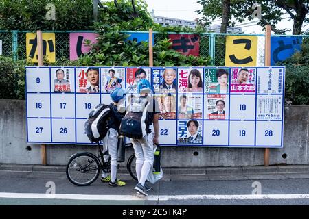 Jugendliche schauen sich ein Wahlboard mit verschiedenen Kandidaten-Plakaten an.Tokyo hält Gouverneurswahlen ab 2020 heute stimmen die Einwohner Tokios für den nächsten Gouverneur, der die japanische Hauptstadt für die kommenden vier Jahre anführt. Stockfoto