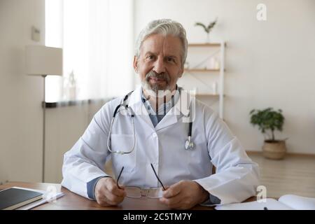 Porträt eines lächelnden männlichen Senior-Arztes am Arbeitsplatz Stockfoto