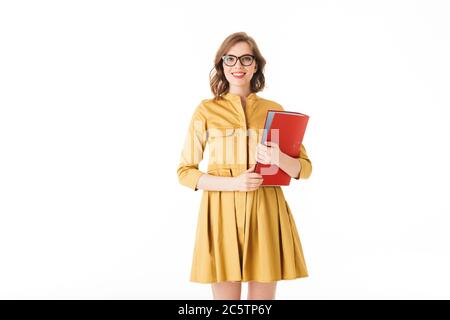 Portrait einer schönen lächelnden Dame in Brillen und Kleid stehen mit rotem Ordner in der Hand und freudig in der Kamera auf weißem Hintergrund Stockfoto