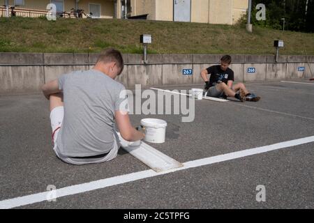 Junge Menschen haben im Sommer Arbeitsplätze zum Malen von Parkleinen gegeben. Stockfoto