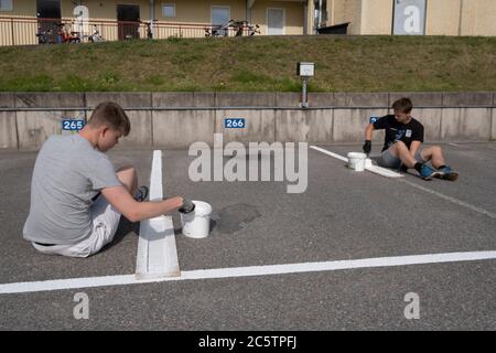 Junge Menschen haben im Sommer Arbeitsplätze zum Malen von Parkleinen gegeben. Stockfoto