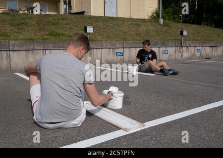 Junge Menschen haben im Sommer Arbeitsplätze zum Malen von Parkleinen gegeben. Stockfoto