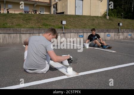 Junge Menschen haben im Sommer Arbeitsplätze zum Malen von Parkleinen gegeben. Stockfoto