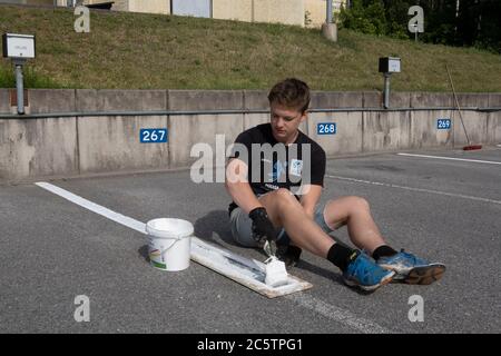 Junge Menschen haben im Sommer Arbeitsplätze zum Malen von Parkleinen gegeben. Stockfoto