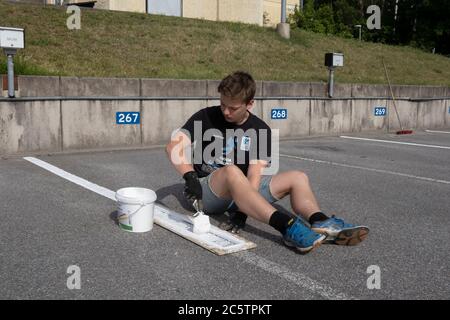 Junge Menschen haben im Sommer Arbeitsplätze zum Malen von Parkleinen gegeben. Stockfoto