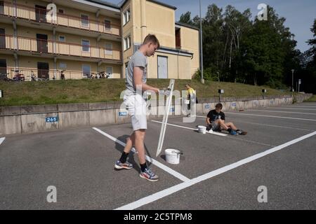 Junge Menschen haben im Sommer Arbeitsplätze zum Malen von Parkleinen gegeben. Stockfoto