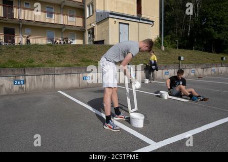 Junge Menschen haben im Sommer Arbeitsplätze zum Malen von Parkleinen gegeben. Stockfoto