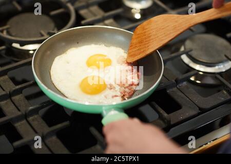 Oben sehen Nahaufnahme von unkenntlich Frau Kochen Frühstück in der Küche mit Schwerpunkt auf Braten Eier in der Pfanne, Copy-Raum Stockfoto
