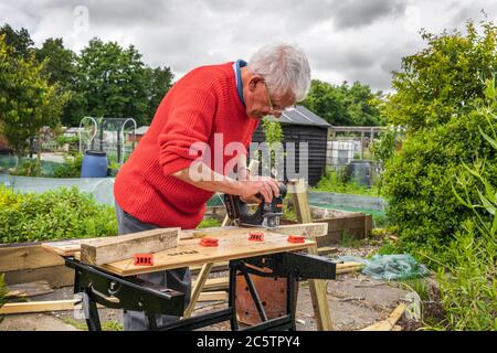 Andy Grayston, der an einer Werkbank arbeitete, die Holzrahmen für seine Zuteilung erhöhte Betten, Eglinton Growers, kilwinning, Ayrshire, Schottland, Großbritannien Stockfoto