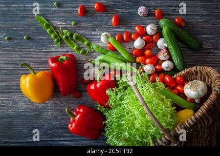 Stillleben mit verschiedenen Arten von frischem Gemüse in einem Korb auf dem Tisch. Draufsicht. Stockfoto