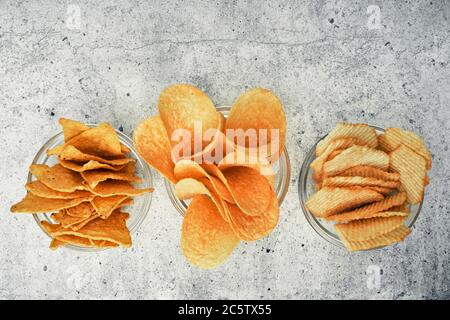 Kartoffel- und Maischips, Snacks, Cracker in transparenten Glasplatten. Mischung aus Snacks. Stockfoto