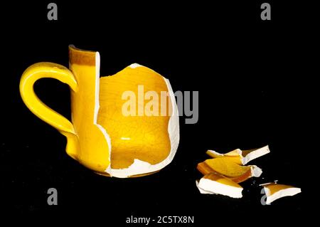 Gebrochene Orange Kaffeetasse auf einem schwarzen Background Stockfoto