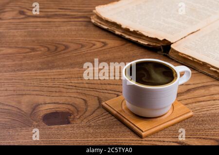 Weiße Tasse Kaffee und geöffnetes Buch. Stockfoto