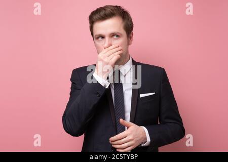 Unzufriedener Mann im Anzug stopft Nase, da riecht etwas stinkt Stockfoto
