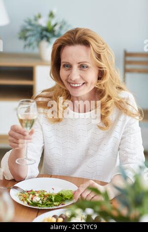 Vertikale Porträt von eleganten reifen Frau heben Champagner Glas beim romantischen Abendessen genießen Stockfoto