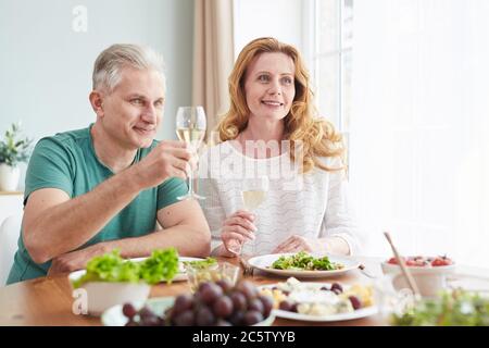 Portrait von liebevollen reifen Paar heben Champagner Gläser während genießen romantisches Abendessen zu Hause, kopieren Raum Stockfoto