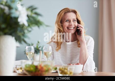Portrait von eleganten reifen Frau sprechen mit dem Smartphone, während das Abendessen zu Hause genießen, kopieren Raum Stockfoto