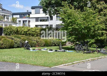 Fahrräder auf dem grünen Gras in der Nähe verteilt Strand Decken withe Familienhäuser auf dem Hintergrund im Sommer während sonnigen schönen Tag geparkt Stockfoto