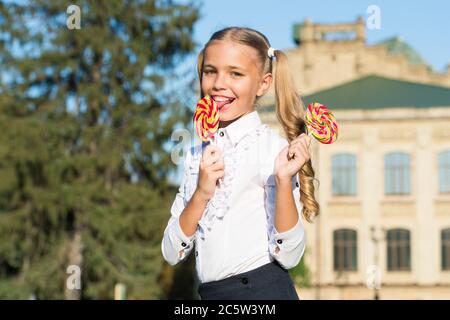 Süßigkeiten machen den Mund glücklich. Kleine Mädchen lecken Süßigkeiten sonnig im Freien. Süßigkeitengeschäft. Lollipop oder Sauger. Zuckerhaltige Leckerbissen. Süßwaren. Essen und Snacks. Süße Welt. Sie verdienen heute eine Süßigkeit. Stockfoto